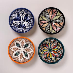 Peut inclure: Quatre bols décoratifs en céramique avec des motifs complexes et colorés. Les bols présentent une variété de motifs, notamment floraux et géométriques, avec des couleurs comme le bleu, l'orange, le vert et le noir. Chaque bol a une couleur et un design de bord uniques.