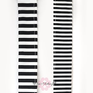 May include: Close-up of two black and white striped fabric straps. The stripes are horizontal and evenly spaced. The fabric appears to be a sturdy material, possibly for a bag or accessory. The text "Sia's Clothing" is visible.