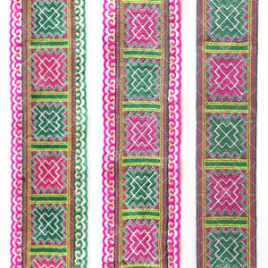 May include: Three decorative ribbons with a repeating geometric pattern in pink, green, and white. The ribbons have a scalloped edge in pink and are bordered by a brown and yellow trim. The design is suitable for crafts and embellishments.