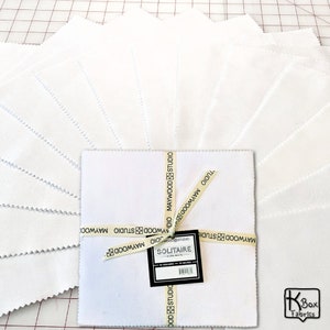 May include: A pack of 42 white 10-inch fabric squares, tied with a ribbon and labeled "Solitaire Ultra White" by Maywood Studio.