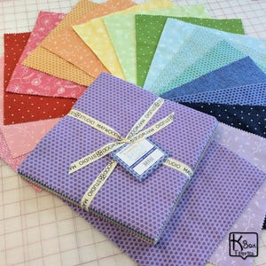 May include: A collection of colorful fabric squares arranged in a fan shape. The squares are various colors, including red, pink, orange, yellow, green, blue, and purple. A bundle of purple fabric squares with a honeycomb pattern is tied with a ribbon.