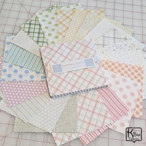 May include: A collection of fabric squares in various pastel colors and patterns, including polka dots, stripes, and plaid. The fabric squares are arranged in a circular pattern. The label reads "Kimberbell Basics Lullaby".
