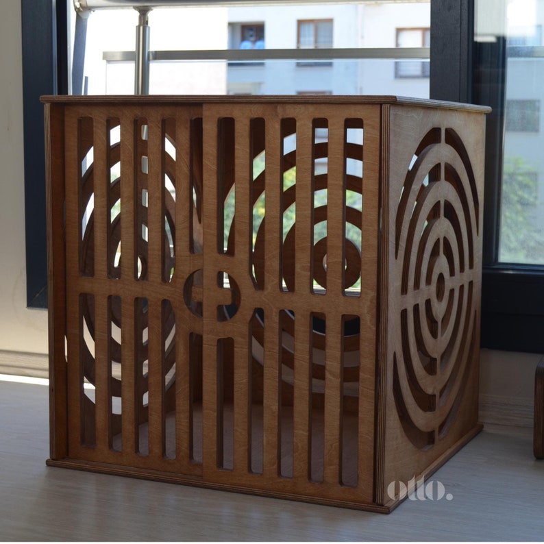 May include: A wooden storage box with a geometric pattern cut out on the front and sides. The box is made of light brown wood and has a rectangular shape.