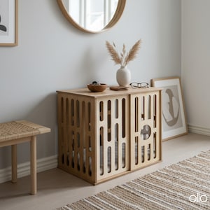 May include: A light wood dog crate with a geometric design. The crate has sliding doors and is topped with a small vase, bowl, and other decorative items. A woven rug and bench are in the foreground.