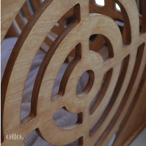 May include: A close-up of a wooden toy with a circular design. The toy is made of light brown wood and has a series of concentric circles cut into the surface. The circles are arranged in a spiral pattern, creating a visually interesting design. The toy is made of plywood and has a natural wood finish.