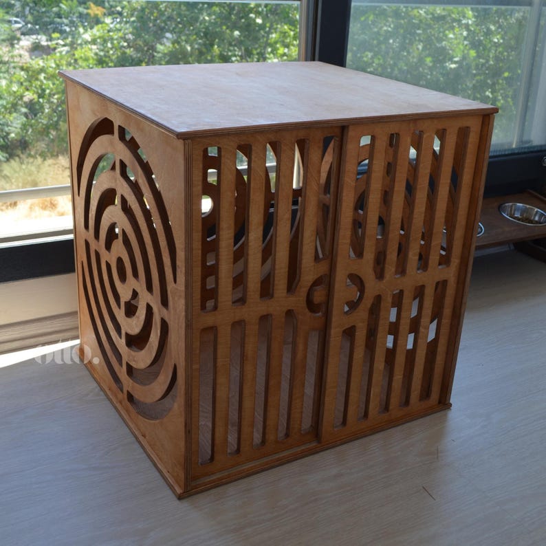 May include: A wooden pet crate with a geometric design on the front and sides. The crate is made of plywood and has a natural wood finish.