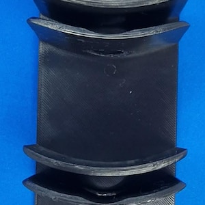 May include: A black, vertically oriented wall-mounted storage rack featuring four distinct, curved, semi-circular compartments stacked in a column. Each compartment includes a circular mounting hole at the base for secure attachment to a flat surface.