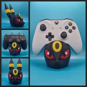 Puede incluir: Un soporte de impresión 3D negro y amarillo con forma de personaje Pokemon con ojos rojos. Un mando Xbox blanco descansa sobre el soporte.