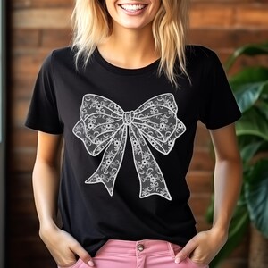 May include: A black t-shirt featuring a white lace bow design.