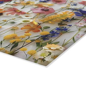 May include: A close-up of a pressed flower arrangement featuring a variety of colours, including pink, yellow, blue, and white. The flowers are arranged in rows on a white background.