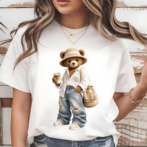Puede incluir: Camiseta blanca con un oso de dibujos animados que lleva un sombrero de paja, una camisa blanca, vaqueros rotos y zapatillas deportivas. El oso sostiene una taza de café y un bolso tote beige con la letra "D".