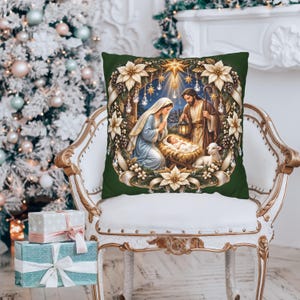Könnte beinhalten: Ein quadratisches Dekokissen mit dunkelgrünem Hintergrund und einem aufgedruckten Krippenspiel. Die Illustration zeigt Maria, Josef und das Jesuskind in einer Krippe, umgeben von einem Kranz aus weißen Weihnachtssternen und Tannenzapfen.