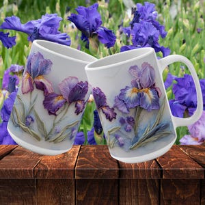 May include: Two white ceramic mugs featuring a floral design of purple and white irises. The mugs are resting on a wooden surface.