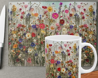 May include: A white ceramic mug with a colorful floral print featuring a variety of dried flowers, including pink, purple, yellow, and blue flowers. The mug is on a gray surface with a matching floral print cutting board.