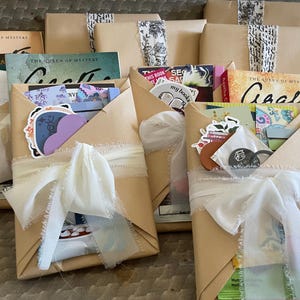 May include: Five wrapped books with brown paper and white ribbon. Each book has a different title and cover art. The books are decorated with stickers and other embellishments.