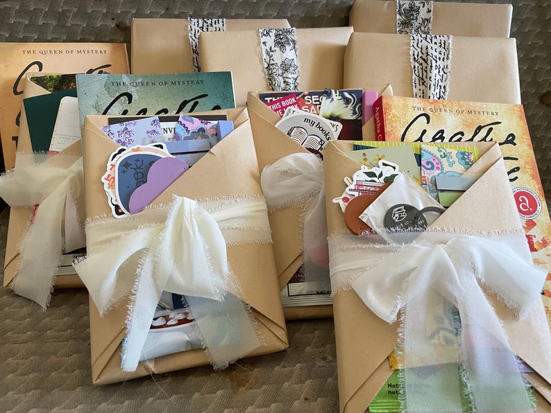 May include: Five wrapped books with brown paper and white ribbon. Each book has a different title and cover art. The books are decorated with stickers and other embellishments.