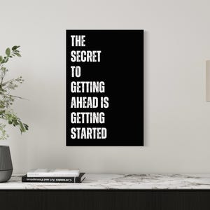 May include: Black and white motivational quote poster with the text "The Secret to Getting Ahead is Getting Started".