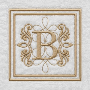 Op de afbeelding: Witte vierkante handdoek met een goud geborduurde letter "B" in een decoratief kader. Het ontwerp omvat sierlijke krullen en een dubbele rand, wat een klassieke en elegante uitstraling creëert. De handdoek is gemaakt van zacht, getextureerd materiaal.