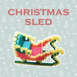 May include: A colorful Christmas sled made of small, fused plastic beads. The sled is red, yellow, green, and blue, with the words "CHRISTMAS SLED" in red letters above it. The background is light blue with Christmas-themed illustrations.