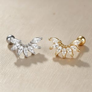 May include: Two stud earrings featuring a curved fan design set with marquise-cut clear cubic zirconia stones. One earring has a silver-tone metal finish, while the other has a gold-tone metal finish. Both include a round ball backing.