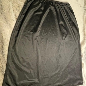 May include: Black slip skirt with a lace trim. The skirt is made of a smooth, silky fabric.