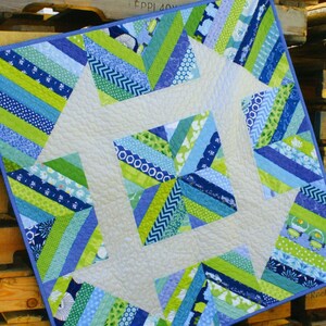 May include: A quilt pattern titled "Churndash Court" by Sassafras Lane Designs. The quilt is made with blue, green, and white fabric and features a geometric design.