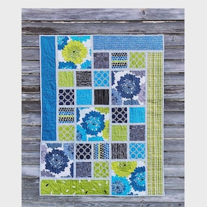 May include: A colorful quilt with the text "KWIK SHIFTED BLOCKS". The quilt features a patchwork design with squares in shades of blue, green, gray, and black. Floral patterns and geometric designs are incorporated throughout the quilt.