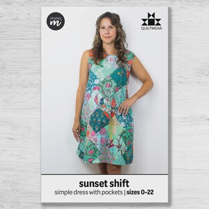 May include: A woman wearing a sleeveless patchwork dress with a floral and bird pattern. The dress is in shades of teal, pink, and green. The image includes the text "sunset shift" and "simple dress with pockets | sizes 0-22". The image also includes the logos for "studio m" and "QUILTWEAR".