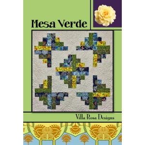 May include: A quilt pattern titled Mesa Verde by Villa Rosa Designs. The cover features a light-colored quilt with five geometric blocks made of blue, green, and yellow floral fabrics, set against a cream background with swirling stitching.