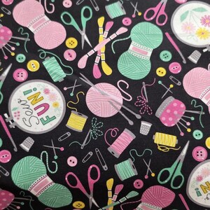 May include: A black fabric featuring a repeating pattern of sewing and knitting supplies including pink and mint green yarn balls, yellow and pink spools of thread, scissors, thimbles, and embroidery hoops with the text Sew FUN! in colorful letters.