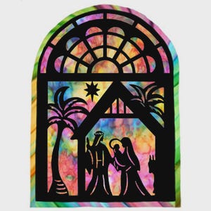 May include: Black silhouette of a Nativity scene within a stained-glass window design. The window features a colorful, tie-dye-like background with a star, palm trees, and the Holy Family. The arched window frame has a decorative top.