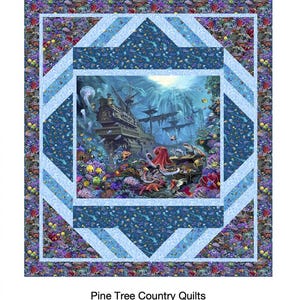 Peut inclure: Une courtepointe Deep Sea Treasure représentant une scène sous-marine détaillée avec un navire coulé, de la vie marine et des récifs coralliens. La courtepointe a une bordure géométrique bleue et blanche et le texte "Deep Sea Treasure".