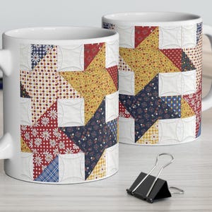 May include: Two white ceramic mugs with a patchwork star design. The star pattern features a mix of red, blue, yellow, and white fabrics. The mugs are on a light-colored wooden surface.