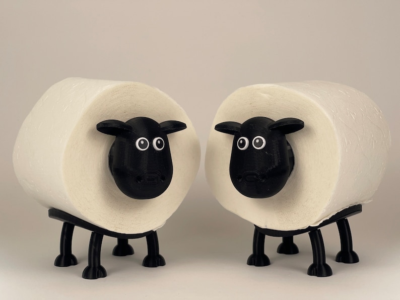 Puede incluir: Dos rollos de papel higi&eacute;nico blancos con caras y patas de ovejas negras. Las ovejas tienen ojos y narices negros.