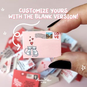 A hand holds a customizable blank miniature Valentine's Day envelope by Aninka Miller Minis, featuring two cute illustrated cats and red hearts. Text reads "Customize yours with the blank version!". Ideal DIY printables for dollhouses in 1:6 and 1:12 scales, perfect for creating personalized romantic doll stationery and love letters.