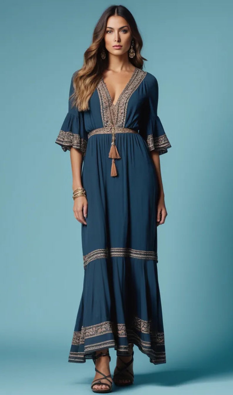 Puede incluir: Un vestido largo de maxi azul teal fluido con escote en V y detalles bordados. El vestido tiene una cintura ajustada con un lazo de borla y una falda fluida con capas escalonadas.