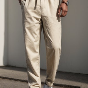 Peut inclure: Pantalon d&eacute;contract&eacute; beige avec une taille &agrave; cordon et un motif subtil en chevrons. Le pantalon est port&eacute; avec des baskets blanches.