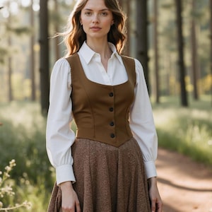 May include: A brown fitted vest with a white button-up shirt underneath and a brown skirt. The person is standing in a forest setting.