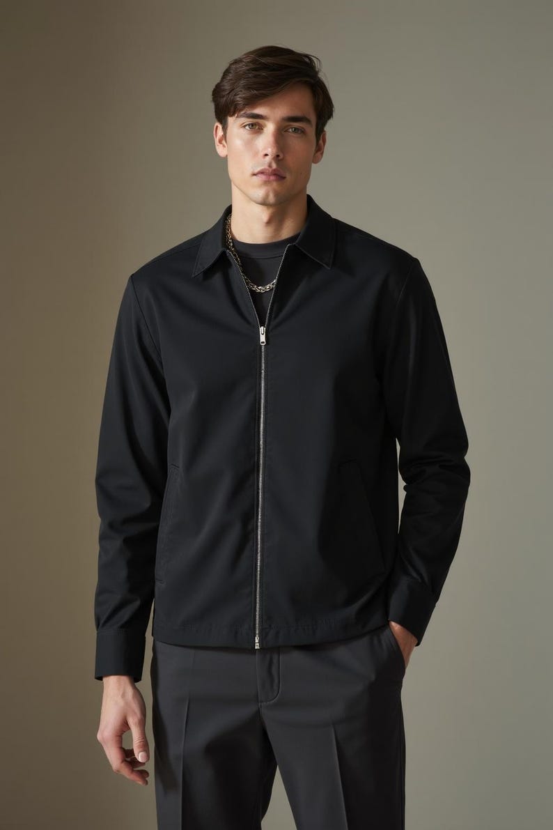 May include: A black zip-up jacket with a collared neckline. The jacket has a zipper closure and long sleeves.