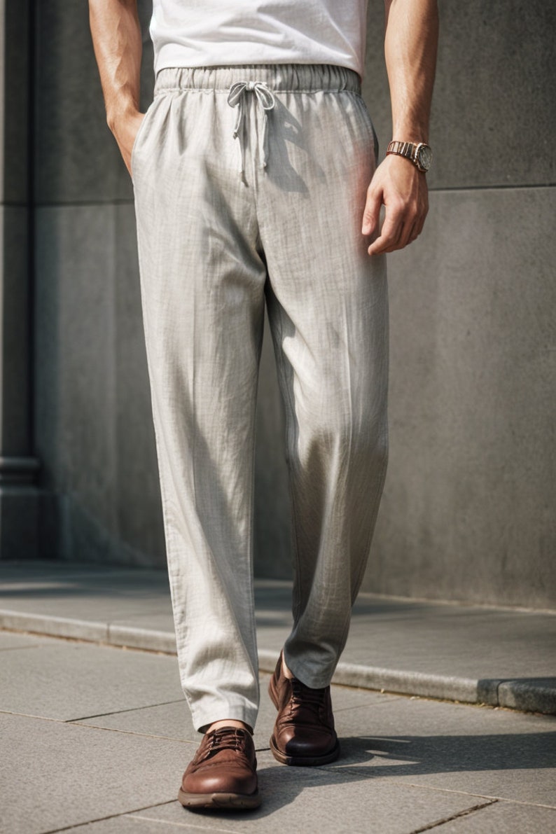 Peut inclure: Un pantalon en lin gris clair avec une taille &agrave; cordon. Le pantalon a un motif &agrave; rayures subtiles et est port&eacute; avec des chaussures en cuir marron.