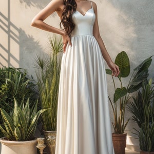 Könnte beinhalten: Ein weißes Satin-Hochzeitskleid mit einem herzförmigen Ausschnitt und einem fließenden Rock. Das Kleid ist ärmellos und hat ein schlichtes Design.