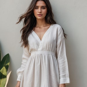 Puede incluir: Un vestido blanco de lino con escote en V, mangas largas y cintura ajustada. El vestido tiene una falda fluida y un corte holgado.