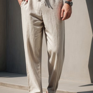 Peut inclure: Pantalon en lin beige avec une taille &agrave; cordon et une coupe d&eacute;contract&eacute;e. Le pantalon est pr&eacute;sent&eacute; sur un mannequin portant des chaussures en cuir marron.