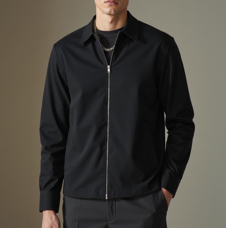 May include: A black zip-up jacket with a collared neckline. The jacket has a zipper closure and long sleeves.