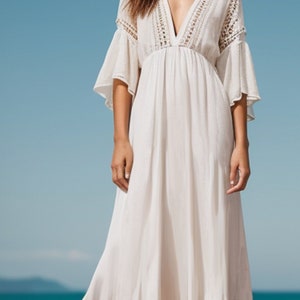 Puede incluir: Un vestido maxi blanco con escote en V y detalles de crochet. El vestido tiene una silueta fluida y es perfecto para una boda en la playa o una fiesta de verano.