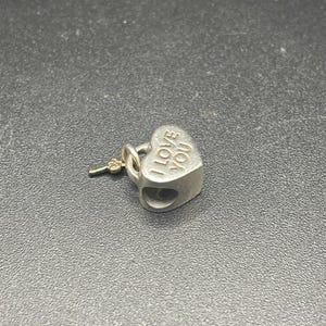 May include: Silver heart-shaped charm with a key attached. The charm has the words "I Love You" engraved on it.