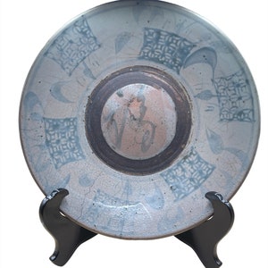 Peut inclure: Une assiette en céramique bleue et blanche avec un motif géométrique. L'assiette est sur un support noir.