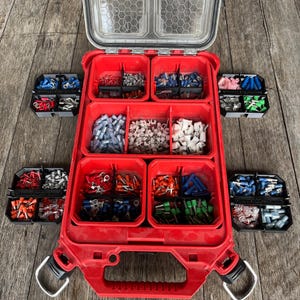 May include: A red storage case with a clear lid, containing compartments filled with electrical connectors. Smaller black containers with more connectors are positioned around the main case. The image displays an organised selection of electrical components.
