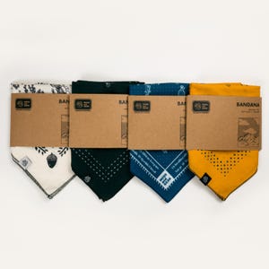 Pode incluir: Quatro bandanas em v&aacute;rias cores: creme com padr&atilde;o de folhas e bolotas pretas, verde escuro com costuras brancas, azul marinho com texto branco e amarelo mostarda com pontos pretos. Cada bandana &eacute; embalada com uma etiqueta de cart&atilde;o castanho.