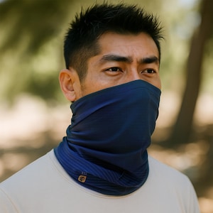 May include: A person wearing a navy blue neck gaiter with a subtle striped pattern. The gaiter is made of a soft, breathable fabric and is designed to be worn as a face mask, neck scarf, or headband.